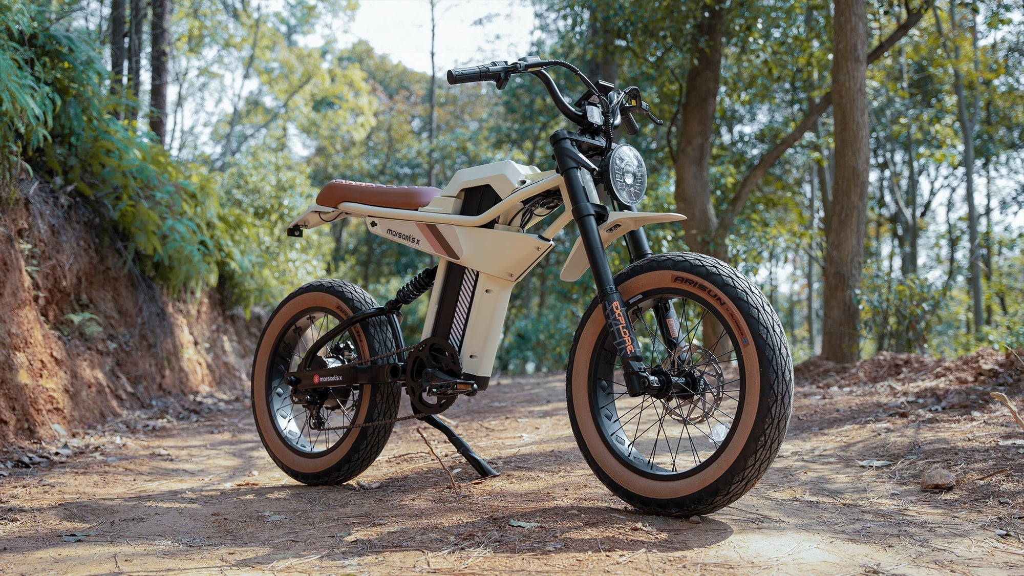  A rugged electric motorcycle parked on a dirt path in a forest.