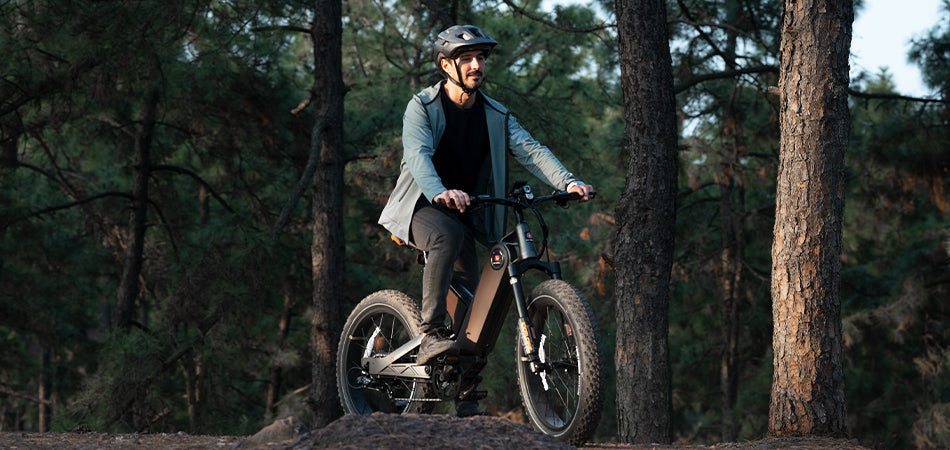 A man riding an electric bicycle in a forest.